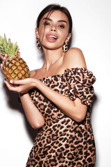 Beautiful sexy woman with pineapple in hands in a leopard dress and earrings, with classic smokey...