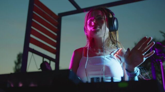 Cool dj is working in a nightclub, standing at turntables, creating a dance music set - nightlife concept 4k footage.