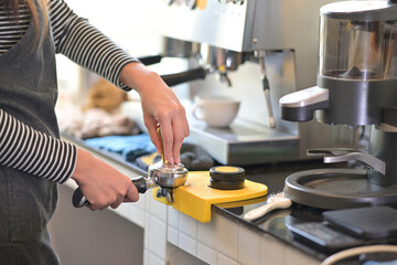 Closed up with professional female barista hand make a coffee with coffee tamper in restaurant pub or coffee shop.