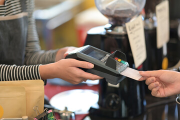Closed up with shopkeepers accepting customer payment via credit card with EDC machine in cafe.