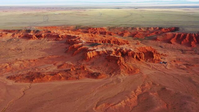 Aerial around view of the Bayanzag flaming cliffs at sunset in Mongolia, found in the Gobi Desert, 4k