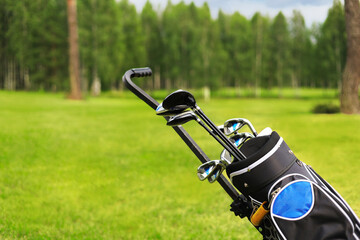 Golf bag and clubs in front of de focused green with sand traps