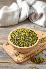 Green mung beans in a bowl on a gray wooden table. Legume plant for a healthy diet closeup	