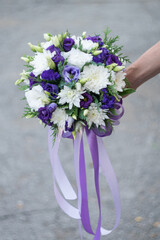 Beautiful stylish round wedding bouquet of violet and white flowers, blurred background, selective focus