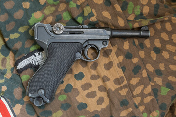 German Parabellum pistol on the background of military camouflage. Reconstruction of the combat...