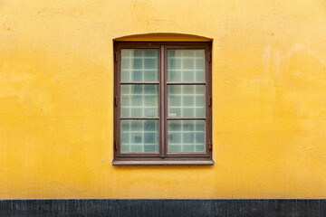 Fototapeta na wymiar Double casement window on yellow concrete wall of house building. Architecture background