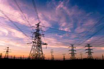 A silhouette of an electric tower against a beautiful sunset background