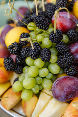 Dish with fruits and berries: grapes, blackberries, strawberries, peaches. wine snacks