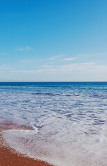 Beautiful sea and ocean landscape, blue sky and foamy wave. Vertical shot. Atlantic coast in Portugal