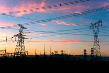 A silhouette of an electric tower against a beautiful sunset background
