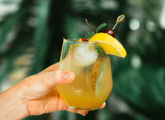 Selective focus hand hold mocktail or cocktail with green nature background.