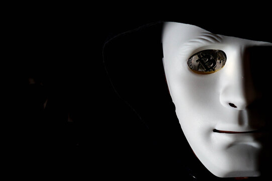 Anonymous careta blanca ojo con moneda de bitcoin con capucha y fondo negro. Hombre Anonymous careta blanca y moneda de bitcoin en lugar del ojo con capucha y fondo negro.