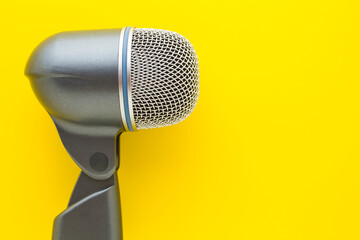 Flat lay of big vocal microphone on yellow background.