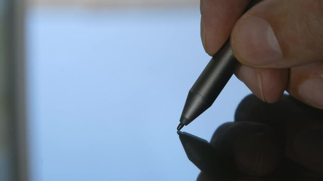 Close-up of hand drawing on a digital tablet with a stylus. Macro view. An artist or a retoucher working on a graphic tablet.