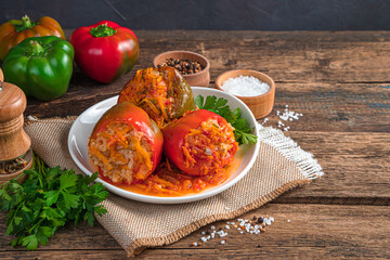 Bell pepper stuffed with turkey, rice and vegetables on a brown wooden background.