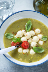 Close-up of vegetable soup with addition of scamorza cheese and fresh green basil, vertical shot