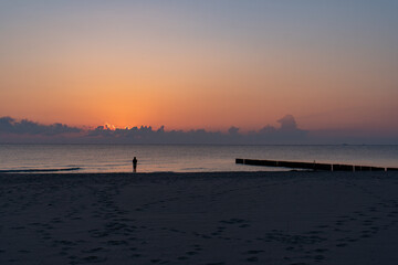 Naklejka premium Woman walking on tropical beach at sunrise