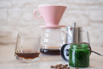 Selective focus on A glass of coffee with blur pour over Dripper and hand coffee grinder and kettleequipment on the table