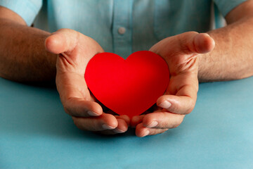 Philanthropy and charity concept. Hands offering a paper heart. Selective focus.