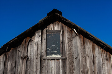 Fototapeta na wymiar fragment of a wooden barn with a wooden old roof on the background of the sky