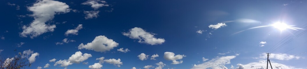 Naklejka na ściany i meble Panorama of the sky. Fluffy clouds with the sun.