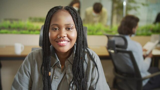 An attractive woman is sitting on the chair and looking to the camera