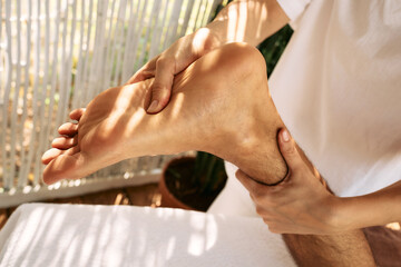 Foot massage with massage oil for man while relaxing and resting at spa on vacation