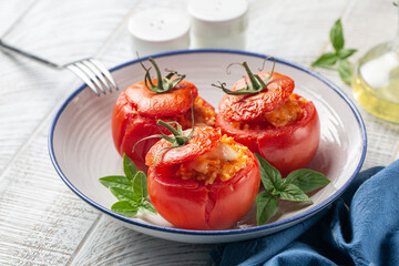 Baked stuffed tomatoes with rice and cheese. Selective focus, close-up. White table.