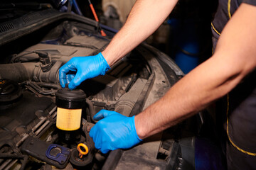 Replacing the oil filter. Specialist auto mechanic in the car service repairs the car.