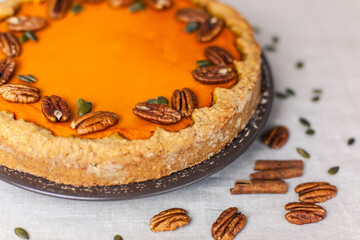 Pumpkin homemade pie on a gray linen background with top view of food ingredients for decoration