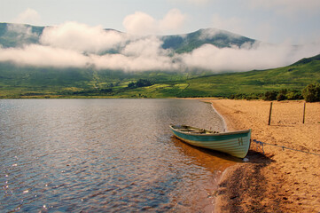Beautiful landscape scenery of old wooden boat on the sandy beach of Loch Na Fooey in connemara National park in county Galway, Ireland 