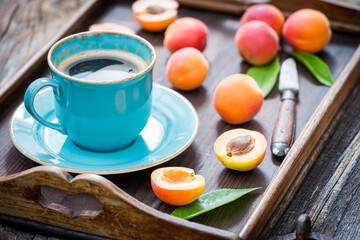 Hot coffee and plums on wooden table