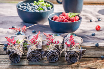 Raspberries, blueberries, napkins and cutlery in summer garden