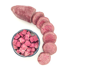 Purple yams are whole and diced on a bowl isolated on a white background. Space for text. Purple sweet potatoes. Top view. Vegan fruit and healthy fruits concept