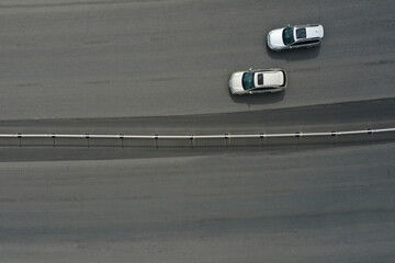 Aerial top view of 2 white cars driving on the highway