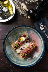 two bruschettas with beef tartare on a plate top view, flat lay