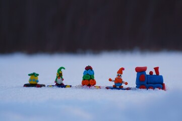 Toy train with Christmas toys on the background of snow.
