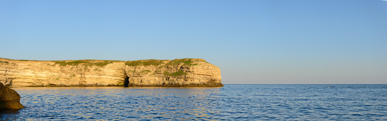 Fototapeta na wymiar Берег моря с крутыми скалами летним вечером