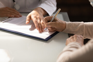 Hands of woman filling document at appointment in doctor office. Therapist, physician helping...