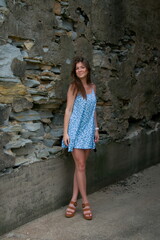 Fototapeta na wymiar a pretty young woman in a blue dress posing in an alley way.