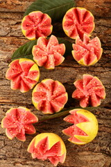 Fototapeta na wymiar Delicious ripe sweet wild red guava fruits slices on a wooden backgrund.
