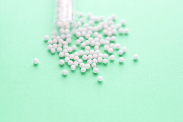 Homeopathy medicine alternative herbs. Homeopathic globules and glass bottle on a green background. Health care and medicine concept.	