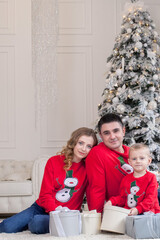 Christmas. Family. Happiness. Portrait of dad, son sitting on a floor at home near the Christmas tree, all are smiling