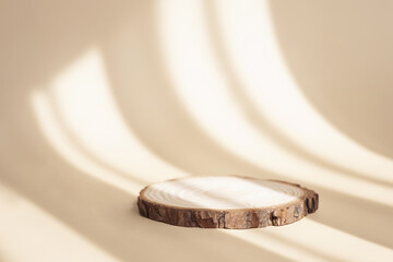 Natural round wooden stand for presentation and exhibitions on pastel beige background with shadow....