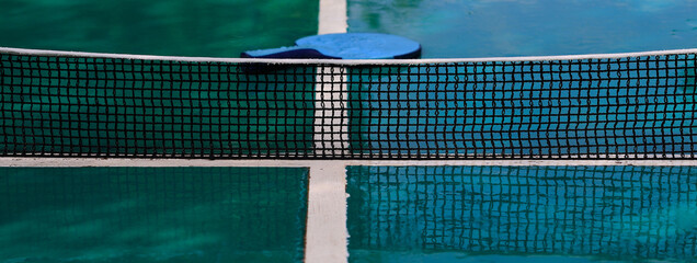Close-up on rain-soaked ping pong table, dominance of gray / blue colors.