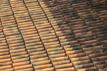 Roof of tiles seen from above, a mixture of warm colors, lights and shadows.