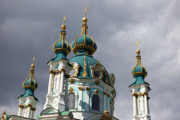 The domes of the ancient St. Andrew's Church, illuminated by the sun against the background of dark...