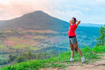 Fototapeta premium Female trail runners wearing pink runners, sportswear doing a warm-up gesture. on the gravel ground on a high mountain with a happy mood, on a clear day Behind is a mountain view.