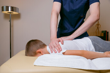 Obraz na płótnie Canvas Doctor osteopath masseur treats the spine after injury, manual therapy for a child