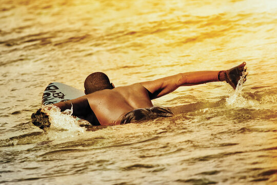 Sporty man on a surfboard at sunset, Malika beach, Senegal